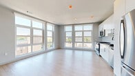 Located at 833 Summer St in Stamford, Connecticut, this modern 2-bedroom, 2-bathroom residence offers a thoughtfully designed open-concept layout with contemporary finishes throughout. Light hardwood flooring flows seamlessly across the entire space, complementing the bright, airy ambiance created by expansive floor-to-ceiling windows that frame sweeping views of the Stamford cityscape and surrounding greenery.

The kitchen and living area form a cohesive, open space ideal for both daily living and entertaining. The kitchen is outfitted with sleek white high-gloss cabinetry, a white subway tile backsplash, and a full suite of stainless steel appliances, including a gas range, built-in microwave, dishwasher, and French door refrigerator.

Both bedrooms are generously proportioned, with the primary bedroom offering corner windows that flood the room with natural light and provide panoramic urban views. Each bedroom is served by a dedicated closet. The primary bathroom features an elegant marble-tiled walk-in shower and a white vanity topped with a backlit mirror. The second bathroom is equally well-appointed with large-format tile flooring, a white vanity, and a matching backlit mirror, offering a clean and functional design.