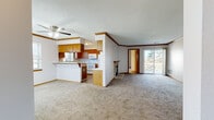 This 3-bedroom, 2-bathroom home delivers a practical and comfortable layout across a single floor. The open-concept living and kitchen area serves as the heart of the home, featuring warm wood cabinetry, a breakfast bar, and white appliances. A textured ceiling with crown molding and a ceiling fan add character to the space, while a fireplace with a stone surround anchors the living room. Sliding glass doors lead to an outdoor balcony, filling the area with natural light and providing views of surrounding greenery.

Carpeted throughout, the bedrooms are generously sized and bright, each featuring windows that invite natural light. The spacious primary bedroom includes access to a well-appointed bathroom with a wide vanity, wood cabinetry, and a full tub-shower combination. Two closets provide ample storage, including a walk-in closet with built-in wire shelving. A second full bathroom serves the remaining bedrooms.

The dedicated laundry room houses a full-size washer and dryer alongside a water heater, offering added convenience. A carpeted staircase with a wooden handrail completes the interior. The home's neutral palette and consistent wood trim details create a cohesive and inviting atmosphere throughout.