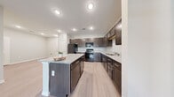 This single-story residence offers a practical and cohesive layout across two bedrooms and two bathrooms. Light-toned wood-style flooring runs throughout the main living areas, creating a clean, consistent aesthetic that ties each space together.

The kitchen is a standout feature, appointed with rich dark espresso cabinetry, granite-style countertops, and a full suite of black appliances including a refrigerator, range, microwave, and dishwasher. A central island provides additional prep and seating space, while recessed lighting ensures the kitchen is well-illuminated. The kitchen opens naturally toward the living area, which benefits from a ceiling fan and a glass-paned entry door that draws in natural light.

The primary bedroom is a comfortable, well-proportioned retreat featuring a ceiling fan, a window with outdoor views, and access to a walk-in closet equipped with wire shelving systems for organized storage. The en-suite bathroom includes a granite-top vanity with dark cabinetry, a glass-enclosed walk-in shower, and tile flooring.

The second bathroom mirrors the design aesthetic with matching dark cabinetry, a granite-top vanity, and a shower-tub combination. Built-in shelving adjacent to the vanity adds practical storage. Two closets serve the residence, and a hallway connects the bedrooms efficiently. The overall ambiance is clean, neutral, and move-in ready.