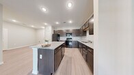 This single-story residence offers a practical and cohesive layout across two bedrooms and two bathrooms. Light-toned wood-style flooring runs throughout the main living areas, creating a clean, consistent aesthetic that ties each space together.

The kitchen is a standout feature, appointed with rich dark espresso cabinetry, granite-style countertops, and a full suite of black appliances including a refrigerator, range, microwave, and dishwasher. A central island provides additional prep and seating space, while recessed lighting ensures the kitchen is well-illuminated. The kitchen opens naturally toward the living area, which benefits from a ceiling fan and a glass-paned entry door that draws in natural light.

The primary bedroom is a comfortable, well-proportioned retreat featuring a ceiling fan, a window with outdoor views, and access to a walk-in closet equipped with wire shelving systems for organized storage. The en-suite bathroom includes a granite-top vanity with dark cabinetry, a glass-enclosed walk-in shower, and tile flooring.

The second bathroom mirrors the design aesthetic with matching dark cabinetry, a granite-top vanity, and a shower-tub combination. Built-in shelving adjacent to the vanity adds practical storage. Two closets serve the residence, and a hallway connects the bedrooms efficiently. The overall ambiance is clean, neutral, and move-in ready.