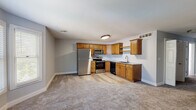Located at 2265 S Koke Mill Rd in Springfield, Illinois, this single-floor unit offers a practical and well-appointed layout throughout. The kitchen serves as a functional hub, featuring warm oak cabinetry, granite-style countertops, and a full suite of stainless steel appliances including a refrigerator, electric range, over-the-range microwave, and dishwasher. Light wood-tone flooring anchors the kitchen area, transitioning to plush carpet in the adjoining living and bedroom spaces.

The bedrooms are finished with soft gray carpet and cool-toned walls, each equipped with ceiling fans for year-round comfort. One bedroom features a charming bay window arrangement that draws in generous natural light and provides an open, airy feel. A walk-in closet is accessible from the primary bedroom, adding functional storage. Additional rooms also benefit from standard windows fitted with blinds.

The bathroom includes a wood-toned vanity with a light countertop, a round mirror, wood-look flooring, and a glass-enclosed shower, creating a clean and cohesive aesthetic. An outdoor deck extends the living space, offering views of a grassy yard and surrounding greenery under open skies.