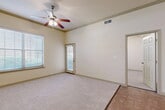This well-designed one-bedroom, one-bathroom residence in Lewisville, TX offers a practical and comfortable layout across a single floor. The living room features plush carpeting, crown molding, a ceiling fan with light fixture, and large windows fitted with blinds that invite generous natural light. A sliding glass door provides access to the outdoors, enhancing the sense of openness. The galley-style kitchen is outfitted with rich dark wood cabinetry, granite-style countertops, stainless steel appliances including a range, microwave, and dishwasher, and a double sink — all set atop tile flooring. A peninsula counter connects the kitchen to the dining area, creating a seamless flow. The bedroom is carpeted and features a ceiling fan, a wide window for natural light, and a built-in desk with shelving, offering a functional workspace. The bathroom includes a soaking tub and shower combination with full tile surround, tile flooring, and dark wood vanity cabinetry. Additional highlights include two closets, a dedicated pantry, and an in-unit laundry area, providing ample storage and everyday convenience throughout the home.