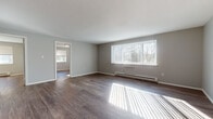 Located at 931 Main St in New Britain, Connecticut, this single-floor unit offers a clean, functional layout with consistent finishes throughout. The spacious living area is highlighted by rich wood-style flooring, neutral gray walls, and a large window fitted with vertical blinds that allows generous natural light to fill the room. A baseboard heating system runs along the walls, ensuring comfortable warmth throughout the space. The open layout connects seamlessly to additional rooms, providing a natural flow through the unit.

The kitchen is well-equipped with light maple cabinetry offering ample storage above and below the counter, complemented by dark stone-look countertops and a textured tile backsplash. Stainless steel appliances, including a refrigerator and electric range, add a modern touch. A stainless steel sink with adjacent counter space rounds out the functional workspace, and wood-style flooring continues from the main living areas into the kitchen.

The bedroom areas are bright and versatile, each featuring the same wood-style flooring, neutral walls, and windows that invite natural light. Baseboard heaters are present in these rooms as well.

The bathroom is finished with large-format gray tile flooring, a white vanity with a mirrored medicine cabinet, and a combined tub and shower, presenting a clean and practical design.