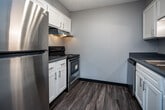 Located at 505 Buckeye Dr in Knoxville, Tennessee, this single-floor unit offers a practical and well-maintained layout with a cohesive design throughout. Rich, dark hardwood-style flooring flows consistently across the living, bedroom, and hallway areas, providing a warm contrast to the cool gray walls and crisp white trim found throughout the space.

The living area is generously proportioned, featuring a ceiling fan with integrated lighting, a textured ceiling, and a window that allows natural light to fill the room. A pass-through counter connects the living area to the kitchen, enhancing the open feel between the two spaces.

The kitchen is efficiently designed with white cabinetry, blue-gray laminate countertops, a stainless steel double-basin sink with under-cabinet lighting, and a stainless steel dishwasher. A range is also present, making the kitchen fully equipped for everyday use.

The bedroom is a comfortable, well-lit room with its own ceiling fan, a window overlooking the exterior, and a closet with a rod for hanging storage. The textured ceiling and consistent flooring tie the room into the overall aesthetic of the unit.

The bathroom features white cabinetry, a blue-gray laminate countertop with an undermount sink, a large mirror, and modern vanity lighting with brushed nickel fixtures, contributing to a clean and updated look.
