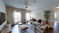 This single-floor residence offers a thoughtfully designed layout that balances modern finishes with a warm, neutral aesthetic throughout. Dark hardwood-style flooring flows through the main living areas and hallway, creating a cohesive and polished foundation.

The kitchen is a standout space, featuring rich dark cabinetry extending to the ceiling, crisp white countertops, a textured tile backsplash, and a full suite of stainless steel appliances, including a range, microwave, dishwasher, and refrigerator. Adjacent to the kitchen, the dining area accommodates a glass-top table beneath a multi-shade chrome chandelier, adding a contemporary touch.

The living room is bright and welcoming, with multiple windows dressed in sheer white curtains, a ceiling fan with a light fixture, and decorative wall art panels. The bedroom features plush carpeting, multiple windows with blinds and curtain rods, a ceiling fan, and direct access to an outdoor area via a glass door. The full bathroom includes a tub-shower combination, a dark vanity with a white countertop, and tall ceilings. Completing the unit is a dedicated laundry room with a full-size washer and dryer.