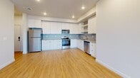 This well-designed single-floor home in Lehi, Utah offers a clean, modern aesthetic throughout its three bedrooms and two full bathrooms. The open-concept kitchen and living area serves as the heart of the home, featuring warm hardwood-style flooring, recessed lighting, and a bright entry door that invites natural light. The kitchen is outfitted with sleek white cabinetry, light gray subway tile backsplash, quartz-style countertops, stainless steel appliances including a refrigerator, range, microwave, and dishwasher, plus built-in open shelving for added functionality. The living area extends naturally from the kitchen, with a built-in shelving nook adding a practical design touch. The spacious primary bedroom is bathed in natural light through multiple windows with blinds and is finished with plush carpeting. It connects to a generously sized walk-in closet with extensive built-in shelving and hanging rods. The primary bathroom features a long dual-sink vanity, large mirror, hardwood-style flooring, and a full bathtub. The second bathroom mirrors the same contemporary style with a single-sink vanity and ample storage. The two additional bedrooms are carpeted, bright, and well-proportioned, each with natural light from sizable windows.