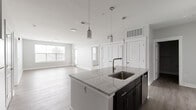 Located at 1420 W Deihl Rd in Naperville, IL, this well-appointed two-bedroom, three-bathroom residence offers a thoughtfully designed single-level layout with modern finishes throughout. The open-concept kitchen and living area serves as the heart of the home, featuring a large center island with striking marble-style countertops, an integrated sink, and stylish pendant lighting overhead. Dark espresso cabinetry contrasts beautifully with the light countertops, while stainless steel appliances complete the contemporary kitchen. Light wood-style plank flooring flows seamlessly through the main living areas, enhancing the bright, airy feel created by multiple windows with natural light. The living room offers direct access to an outdoor area through a glass door. The primary bedroom is a comfortable retreat with plush carpeting, a ceiling fan, and a well-sized window. Each bedroom is supported by dedicated closet space featuring wire shelving systems for organized storage. The bathrooms include subway tile surrounds in the tub/shower areas and dark-vanity cabinetry paired with marble-style countertops. Neutral gray tones carry throughout the interior, creating a clean, cohesive aesthetic ideal for modern living in the heart of Naperville.