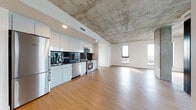 Located in the heart of Oakland at 570 10th St, this contemporary urban residence showcases an industrial-modern aesthetic with striking exposed concrete ceilings throughout. Warm hardwood flooring flows seamlessly across the open-plan living and dining areas, creating an inviting contrast against the raw architectural elements above. Expansive floor-to-ceiling windows flood the space with natural light while framing impressive panoramic views of the Oakland and greater Bay Area skyline.

The sleek, open kitchen is outfitted with high-gloss white cabinetry, dark stone countertops, a bold black tile backsplash, and a full suite of stainless steel appliances, including a refrigerator, range, microwave, and dishwasher. The living area is generous and open, anchored by a concrete structural column that adds to the industrial character of the space.

A private outdoor balcony is accessible through black-framed glass doors, offering additional outdoor space with city views. The bedrooms are bright and airy, each benefiting from large windows overlooking the urban landscape. Two bathrooms serve the residence — one featuring a floating white vanity with tile flooring, and another with a full soaking tub and shower combination. Clean white walls and refined finishes complete this contemporary Oakland residence.