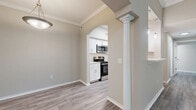 This single-floor, 2-bedroom, 2-bathroom home offers a thoughtfully designed layout with a seamless flow between living spaces. The living and dining areas feature light wood-look flooring, neutral warm-gray tones, and crown molding throughout, creating a polished, cohesive aesthetic. A decorative column and elegant arched passageway connect the main living area to the kitchen, adding a classic architectural touch.

The kitchen is outfitted with white shaker-style cabinetry, light countertops, a subway tile backsplash, and a full suite of stainless steel appliances, including a gas range, microwave, refrigerator, and dishwasher. Wood-look flooring continues through the kitchen, reinforcing the home's consistent design language.

The primary bedroom offers a comfortable, well-proportioned space with plush carpeting, a ceiling fan, and windows that frame natural greenery views. Three closets are distributed throughout the home, including a spacious walk-in closet with wire shelving systems for organized storage.

The second bedroom also features carpeted floors, a ceiling fan, and a large window with vertical blinds and a transom window above for added natural light. Both bathrooms maintain the neutral palette, with wood-look tile flooring and a clean, functional design including a soaking tub and shower combination. A hallway connects the bedrooms, bathrooms, and closets, completing this efficiently organized floor plan.