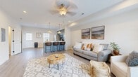 This two-story home in Clarksville, Tennessee offers a practical and well-appointed layout across two floors. The main level features an open-concept living area with light hardwood-style flooring, recessed lighting, and a ceiling fan, creating a bright and welcoming atmosphere. The living space flows seamlessly into the kitchen, which is equipped with stainless steel appliances, blue-gray shaker cabinetry, white countertops, and a peninsula with bar seating illuminated by pendant lighting. A dedicated laundry area with washer hookups is also found on this level, adding everyday convenience. The bathrooms are finished with marble-style countertops, blue-gray vanities, and tiled tub-shower surrounds. The upper floor hosts the bedrooms, including a well-proportioned primary bedroom with carpet flooring, natural light from large windows, and a ceiling fan. Additional bedrooms are similarly finished with carpet, ceiling fans, and windows that bring in natural light. Throughout the home, neutral walls and consistent design choices create a cohesive and move-in-ready aesthetic suited for a range of occupants.