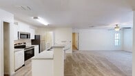 This 950-square-foot, single-floor apartment at MacAlpine Place offers a practical and comfortable layout with 2 bedrooms, 1 bathroom, a combined kitchen and living room, and a dedicated closet. The open-concept kitchen is well-equipped with stainless steel appliances, including a range, over-the-range microwave, and refrigerator, complemented by white cabinetry, stone-look countertops, and a curved breakfast bar peninsula. Wood-look flooring runs through the kitchen area, while plush carpet covers the living room and both bedrooms. The spacious living room receives generous natural light through large windows with outdoor views and features a ceiling fan overhead. The primary bedroom measures 150 square feet and includes a ceiling fan, carpeted flooring, and access to a walk-in closet fitted with wire shelving. The second bedroom also features carpet, a ceiling fan, and corner windows that bring in abundant natural light. The full bathroom is finished with wood-look flooring, a single-sink vanity with stone countertop, white cabinetry, and a shower-tub combination. The unit's neutral color palette and clean finishes create a bright, functional living environment throughout.