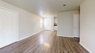 Located at 701 S Juniper St in Foley, Alabama, this single-floor, two-bedroom, one-bathroom residence offers a practical and comfortable layout with consistent wood-look flooring throughout. The open-concept kitchen and living area forms the heart of the home. The kitchen is equipped with white cabinetry extending to the upper walls, dark laminate countertops, a double-basin sink, and a white range, providing ample storage and workspace. The living room features a textured ceiling, a chandelier-style light fixture, and direct access to a private balcony through sliding glass doors that invite natural light and outdoor views of the surrounding greenery. Both bedrooms are fitted with ceiling fans, textured ceilings, and windows that allow natural light to filter in. The primary bedroom includes two closets and offers a comfortable, well-proportioned space. The second bedroom also benefits from natural light and a ceiling fan. The single bathroom features a tub/shower combination, a white vanity with under-sink storage, and wood-look flooring that ties in with the rest of the home. Neutral warm-beige wall tones are carried throughout, creating a cohesive and inviting atmosphere across all rooms.
