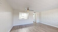 Located at 1039 N Alamo Ave in Tucson, AZ, this 1-bedroom, 2-bathroom residence offers a thoughtfully updated interior with a clean, modern aesthetic throughout. The open-concept living room and kitchen area is anchored by light-toned luxury vinyl plank flooring that runs continuously through the space, complemented by white-painted brick accent walls that add texture and character. A ceiling fan with integrated lighting keeps the living area comfortable, while a large window invites ample natural light. The kitchen is a standout feature, showcasing white shaker-style cabinetry, white subway tile backsplash, a skylight panel for added brightness, and a striking marble-veined quartz peninsula countertop. Stainless steel appliances—including a range, microwave, dishwasher, and refrigerator—complete the modern culinary space. A hallway connects the main living area to the private bedroom, which features the same LVP flooring, white brick walls, a closet, and a window with natural views. Built-in hallway cabinetry provides convenient additional storage. Both bathrooms are finished in crisp white tones, with one featuring a clean soaking tub and tiled surround. The overall ambiance is bright, fresh, and move-in ready.