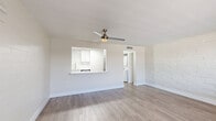 Located at 1039 N Alamo Ave in Tucson, AZ, this 1-bedroom, 2-bathroom residence offers a thoughtfully updated interior with a clean, modern aesthetic throughout. The open-concept living room and kitchen area is anchored by light-toned luxury vinyl plank flooring that runs continuously through the space, complemented by white-painted brick accent walls that add texture and character. A ceiling fan with integrated lighting keeps the living area comfortable, while a large window invites ample natural light. The kitchen is a standout feature, showcasing white shaker-style cabinetry, white subway tile backsplash, a skylight panel for added brightness, and a striking marble-veined quartz peninsula countertop. Stainless steel appliances—including a range, microwave, dishwasher, and refrigerator—complete the modern culinary space. A hallway connects the main living area to the private bedroom, which features the same LVP flooring, white brick walls, a closet, and a window with natural views. Built-in hallway cabinetry provides convenient additional storage. Both bathrooms are finished in crisp white tones, with one featuring a clean soaking tub and tiled surround. The overall ambiance is bright, fresh, and move-in ready.