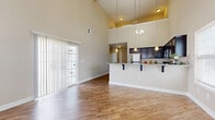 This two-story home is designed with both functionality and comfort in mind, offering a well-thought-out layout across two levels. The heart of the home is the open-concept living and kitchen area, distinguished by dramatic vaulted ceilings that amplify the sense of space and allow natural light to pour in through a sliding glass door fitted with vertical blinds. The kitchen features dark espresso cabinetry, granite countertops, a breakfast bar with pendant lighting, and a full suite of stainless steel appliances including a refrigerator, range, and built-in microwave. Hardwood-style flooring flows throughout the main living areas, complementing the warm, neutral color palette found throughout the home. A dedicated laundry room provides added convenience with side-by-side washer and dryer hookups and wire shelving. The bathroom is finished with tile-surround tub and shower, dark vanity cabinetry, and granite countertops. Bedrooms offer plush carpeting and ceiling fans, with one featuring a generously sized walk-in closet with full wire shelving systems. A hallway connects to a staircase leading between floors. The attached garage provides secure parking and additional storage space with an automatic opener.