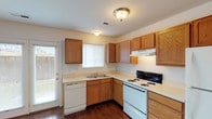 This two-story home offers a practical and well-organized layout across its two floors. The main level features a kitchen equipped with warm-toned wood cabinetry providing ample storage, light-colored countertops, a double-basin sink, a dishwasher, an electric coil range, and a full-size refrigerator. Rich hardwood flooring runs throughout the kitchen, which also benefits from a window and direct door access to the exterior, allowing natural light to filter in. A half bathroom on the main level features hardwood flooring, a wood-vanity with a single sink, and a lighted mirror. The main living area is carpeted and includes a ceiling fan with light fixture, creating a comfortable, open environment.

A carpeted staircase connects the two floors, leading to the upper level where additional carpeted rooms offer versatile living spaces. Each room is served by windows fitted with blinds, providing natural light and exterior views. The upper-level full bathroom includes a combined tub and shower, a wood-vanity, and a mirrored cabinet above the sink. Throughout the home, neutral wall tones and clean finishes create a bright, move-in ready atmosphere suitable for a variety of living arrangements.