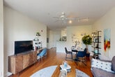 This thoughtfully designed single-floor residence offers a functional and inviting layout that maximizes every square foot. Rich hardwood flooring flows throughout the main living areas, anchoring the open-concept space that seamlessly connects the kitchen, dining, and living areas into one cohesive zone.

The kitchen features crisp white cabinetry, granite countertops, a peninsula with a stainless steel sink, and stainless steel appliances including a refrigerator and range. A galley-style layout along one wall provides ample workspace and storage. The kitchen opens directly to the combined dining and living room, which is brightened by large windows and a sliding glass door that fills the space with natural light. A ceiling fan with track lighting overhead adds both comfort and illumination.

The bedroom is a calm retreat carpeted for comfort, with a window offering natural light and views of greenery. Multiple closets throughout the unit provide generous storage. The bathroom includes a full vanity with cabinet storage, a tub-shower combination, and tile flooring. Additional utility rooms and a dedicated laundry area round out the practical amenities. A hallway connects the private areas to the living spaces, creating a clear and intuitive flow throughout the home.
