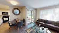 Located at 1907 Night Song Ct in Schaumburg, Illinois, this single-floor residence offers a well-organized and comfortable layout with a cohesive, contemporary aesthetic throughout. The living room is a welcoming centerpiece, featuring light wood-style flooring, neutral warm-toned walls, and generous natural light streaming in through large windows and a sliding glass door that opens to a tree-lined outdoor view. The open dining area adjoins the living space, accompanied by a circular decorative mirror that adds a stylish accent. The kitchen is efficiently designed with crisp white cabinetry, light countertops, and black appliances including a gas range, over-the-range microwave, and refrigerator — offering a clean, high-contrast look. The bedrooms are carpeted for comfort, with each room benefiting from natural light through well-dressed windows with blinds and curtains. The primary bedroom provides a peaceful retreat, while a secondary bedroom includes a closet with built-in rod storage. The bathroom features a full tub-shower combination with clean white tile surround. Throughout the residence, the design maintains a neutral palette with consistent finishes, creating a calm and functional living environment suited for everyday comfort.