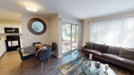 Located at 1907 Night Song Ct in Schaumburg, Illinois, this single-floor residence offers a well-organized and comfortable layout with a cohesive, contemporary aesthetic throughout. The living room is a welcoming centerpiece, featuring light wood-style flooring, neutral warm-toned walls, and generous natural light streaming in through large windows and a sliding glass door that opens to a tree-lined outdoor view. The open dining area adjoins the living space, accompanied by a circular decorative mirror that adds a stylish accent. The kitchen is efficiently designed with crisp white cabinetry, light countertops, and black appliances including a gas range, over-the-range microwave, and refrigerator — offering a clean, high-contrast look. The bedrooms are carpeted for comfort, with each room benefiting from natural light through well-dressed windows with blinds and curtains. The primary bedroom provides a peaceful retreat, while a secondary bedroom includes a closet with built-in rod storage. The bathroom features a full tub-shower combination with clean white tile surround. Throughout the residence, the design maintains a neutral palette with consistent finishes, creating a calm and functional living environment suited for everyday comfort.