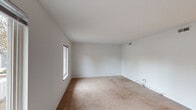 Located at 29 Goldsmith Pl in Newport News, Virginia, this single-floor residence offers a clean, functional layout designed for comfortable everyday living. The interior is finished with neutral white walls and warm beige carpeting throughout the living and sleeping areas, creating a bright and cohesive aesthetic.

The main living area is generously proportioned, benefiting from multiple windows that draw in natural light. A ceiling fan with a built-in light fixture adds both comfort and practicality. An open passageway connects the living space to the kitchen, which features medium-toned wood cabinetry, a light countertop, and black appliances including a refrigerator and range.

The bedroom provides ample space and is notably equipped with two side-by-side closets, offering substantial built-in storage. A large window in the bedroom overlooks the surrounding neighborhood, providing natural light and an outward view.

The full bathroom is finished with light tile flooring, a white vanity with cabinet storage, and a full tub-and-shower combination with a curtain rod — all presented in a clean, all-white palette.

A dedicated laundry area accommodates a stacked washer and dryer unit alongside additional wood cabinetry and counter space with tile flooring, adding significant in-unit convenience. Overall, the space presents a straightforward and practical living environment.