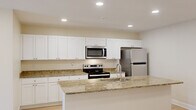 This thoughtfully designed 2-bedroom, 2-bathroom residence in Columbia, SC delivers a functional and modern living experience across a single floor. The open-concept kitchen and living area serves as the heart of the home, featuring a large granite-topped island with an undermount sink, crisp white shaker cabinetry extending to the ceiling, and a full suite of stainless steel appliances including a range, over-the-range microwave, and refrigerator. Light wood-style flooring flows throughout the main living areas, complemented by recessed lighting and ceiling fans that enhance both style and comfort. The living room benefits from abundant natural light through a large window and sliding glass door with vertical blinds, creating a bright and airy atmosphere. Both bedrooms are carpeted and feature ceiling fans with light fixtures and ample natural light from windows. The spacious primary bedroom includes a large window with outdoor views. Each of the two bathrooms mirrors the home's design continuity with granite countertops, white cabinetry, and light wood-style flooring. One bathroom features a walk-in shower, while the other offers a full shower-tub combination. Two dedicated closets provide generous storage throughout the residence.