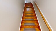 Located at 270 Providence Ave in East Providence, Rhode Island, this one-bedroom, one-bathroom unit offers a practical and well-organized layout across a single floor. A staircase with warm-toned hardwood steps and non-slip treads leads up to the main living level, where neutral-toned walls and consistent finishes create a cohesive feel throughout.

The combined dining and living area provides an open, flexible space for everyday living, with room for both relaxing and dining. The kitchen features warm wood cabinetry, granite-style countertops, and a large window fitted with horizontal blinds that allows natural light to pour in while offering outdoor views of the surrounding neighborhood. Tile flooring grounds the kitchen area, while the rest of the unit transitions to light-toned carpeting.

The bedroom is a generously sized retreat, comfortably accommodating a full furniture arrangement. It includes a large closet with double panel doors, a window with outdoor views, and a wall-mounted air conditioning unit for added comfort. The room is finished with soft carpeting and clean white trim throughout.

The bathroom is bright and clean, featuring a full tub-shower combination with built-in shelving niches and a crisp white surround. The unit also boasts an impressive five closets in total, providing abundant storage throughout. Overall, the space is functional, well-lit, and move-in ready.