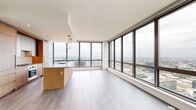 Located in Chicago's vibrant West Loop neighborhood, this high-rise unit at 164 N Peoria Street offers a sleek, modern living experience with thoughtfully designed spaces and stunning panoramic city views. The open-concept living and dining area is anchored by dramatic floor-to-ceiling windows that wrap the corner of the space, flooding the interior with natural light and framing expansive views of the Chicago skyline and surrounding cityscape. Light wood-tone flooring runs throughout, complementing the clean, neutral palette.

The kitchen is a standout feature, centered around a generous island with a stone countertop and warm wood cabinetry that extends to the ceiling. Pendant lighting, a marble-style backsplash, and integrated appliances complete the refined culinary space. The entryway offers a clean, private transition into the home with tile flooring and a solid door entry.

The bedrooms are bright and airy, each benefiting from large windows that continue the theme of abundant natural light and elevated city views. The bathrooms are finished with contemporary fixtures, including a full bath featuring a soaking tub with tiled surround and a warm wood vanity, while the powder room offers a minimalist concrete-look sink and round mirror. Every detail reflects a polished, modern aesthetic throughout.