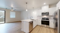 Located at 2121 N 99th Ave in Phoenix, Arizona, this well-appointed one-bedroom, one-bathroom residence offers a clean, modern aesthetic throughout its thoughtfully designed single-floor layout. Light wood-style flooring flows seamlessly across the entire unit, complementing the bright, neutral palette that defines each room.

The open-concept kitchen and living area serves as the heart of the home. The kitchen features crisp white cabinetry, a white quartz peninsula with an undermount sink, stainless steel appliances including a refrigerator, electric range, microwave, and dishwasher, and stylish pendant lighting overhead — all designed for both functionality and visual appeal.

The spacious bedroom receives natural light through a window with blinds and connects directly to a dedicated walk-in closet with built-in shelving, providing generous storage. The full bathroom is finished in a clean, contemporary style with white subway tile in the tub/shower surround, a white vanity with quartz countertop, and wood-style flooring that ties the space together.

Additional highlights include a dedicated laundry area with a full-size washer and dryer, a private balcony, and recessed lighting throughout. The overall ambiance is bright, clean, and move-in ready.