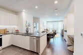 Located in Charlotte's vibrant South End neighborhood, this well-appointed 2-bedroom, 2-bathroom residence offers a thoughtfully designed single-floor layout with modern finishes throughout. The open-concept living area seamlessly connects the kitchen, dining, and living spaces, all anchored by rich hardwood-style flooring and recessed lighting. The kitchen features sleek white cabinetry, dark granite countertops, stainless steel appliances including a French door refrigerator and dishwasher, and a peninsula with bar seating — ideal for casual dining or entertaining. The living room is bathed in natural light from floor-to-ceiling windows that open to a balcony, offering views of the surrounding neighborhood. Both bedrooms are generously sized, each with its own en-suite bathroom and ceiling fan. The primary bath showcases marble-style tile flooring, a floating vanity with granite countertops, and a glass-enclosed walk-in shower. Ample storage is provided by four closets, including a spacious walk-in outfitted with adjustable shelving systems. Additional conveniences include an in-unit laundry area and a dedicated utility room, rounding out this polished and functional Charlotte residence.