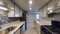 This single-floor residence at 2745 Coldstream Lane in Columbus, Ohio presents a thoughtfully updated interior with a cohesive, modern aesthetic throughout. The kitchen is a standout feature, outfitted with gray shaker-style cabinetry, light granite countertops, a mosaic tile backsplash, and stainless steel appliances including a refrigerator, dishwasher, and gas range. Large-format tile flooring runs underfoot, and recessed lighting illuminates the space effectively. A pass-through opening connects the kitchen to the adjoining living area, enhancing the sense of openness.

The main living area is bright and generously sized, featuring light-toned wood-style flooring, neutral warm-gray walls, and multiple windows that invite natural light. A textured ceiling adds subtle visual interest throughout the common areas.

The bedrooms are carpeted and well-proportioned, with windows providing natural light and outdoor views. One bedroom offers direct access to a bathroom, while additional closet space is accessible nearby.

The bathroom features large-format tile flooring, a granite-topped vanity with gray cabinetry, and a full mirror — consistent with the updated finishes seen throughout the unit. Overall, the space presents a clean, modern character with practical, well-maintained finishes at every turn.