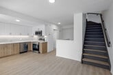 Located at 99 Milford Ave in Waterloo, Ontario, this modern two-storey unit offers 3 bedrooms and 2 bathrooms distributed across two well-proportioned floors. Light hardwood-style flooring runs throughout, lending a clean, cohesive aesthetic to the entire space.

The main floor houses a contemporary kitchen equipped with stainless steel appliances — including a refrigerator, electric range, over-the-range microwave, and dishwasher — complemented by two-tone cabinetry featuring white upper cabinets and warm wood-finish lower cabinets, a tile backsplash, and light countertops. A living area and hallway complete the main level.

Upstairs, the three bedrooms are bright and neutrally finished with crisp white walls. The primary bedroom includes access to a dedicated closet, while another bedroom features sliding glass doors opening onto a private balcony with outdoor views. A hallway connects the upper-floor rooms, with a full bathroom featuring a soaker tub with tiled surround, and a second bathroom with a warm wood vanity, white countertop, and large mirror. The upper landing offers an open feel with natural light filtering in from a window.

Throughout, the unit maintains a clean, contemporary design with a neutral palette, recessed lighting, and modern fixtures, making it a functional and well-appointed multi-level residence.