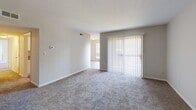Located at 6525 Greenway Dr in Roanoke, Virginia, this single-floor residence offers a well-organized layout designed for comfortable everyday living. The entryway opens into a spacious carpeted living area filled with natural light, highlighted by a sliding glass door fitted with vertical blinds that provides outdoor access and a bright, airy atmosphere. Adjacent to the living space, the galley-style kitchen is thoughtfully appointed with white shaker cabinetry, stone-patterned countertops, a stainless steel sink, and black appliances including a refrigerator and dishwasher. Wood-look flooring runs throughout the kitchen, which also features a door leading to an exterior utility or storage area. The bedrooms are carpeted and offer a calm, neutral palette with beige and warm-toned walls. Each bedroom includes closet storage, and the primary bedroom benefits from direct access to a private bathroom as well as a walk-in style closet. The bathrooms feature wood-look flooring, white vanities, and clean, minimalist finishes including brushed nickel hardware and grab bars. Throughout the residence, consistent neutral tones, plush carpeting in living and sleeping areas, and updated fixtures contribute to a move-in-ready, functional living environment.
