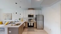Located at 1969 Randall Rd in Cleveland, Ohio, this single-floor residence presents a cohesive modern design defined by clean lines, neutral tones, and quality finishes. The open-concept kitchen serves as a central highlight, outfitted with a two-tone cabinetry scheme pairing white upper cabinets with warm wood-toned lower cabinets. Light quartz countertops, a subway tile backsplash, and a full suite of stainless steel appliances — including a refrigerator, electric range, and over-the-range microwave — complete the space. Sleek pendant lights hang above the undermount sink, adding an element of contemporary style. Light-toned luxury vinyl plank flooring flows through the kitchen and living areas, contributing to a bright, airy feel.

The bedroom offers a calm, restful atmosphere with soft carpet underfoot, crisp white walls, and a generously sized window that invites natural light and outdoor views. The bathroom is tastefully appointed with a wood-toned vanity, white countertop, and a glass-enclosed walk-in shower featuring large-format tile surround. Recessed lighting and light wood-style flooring maintain the home's consistent, modern aesthetic throughout. The overall ambiance is clean, contemporary, and thoughtfully designed.