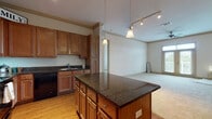 Located at 921 S Orlando Ave in Maitland, Florida, this single-floor residence offers a well-designed layout with a seamless flow between living and kitchen spaces. The kitchen is a standout feature, showcasing rich warm-toned wood cabinetry, dark granite countertops, and a central island with pendant lighting overhead. Stainless steel appliances, including a refrigerator and microwave, complement the black range and dishwasher, while track lighting and hardwood-style flooring add to the kitchen's polished character. Crown molding throughout the space provides an elevated architectural detail.

The open living area extends naturally from the kitchen, featuring plush carpeting, crown molding, a ceiling fan, and glass doors that open to a private balcony, allowing natural light to fill the room. The primary bathroom is well-appointed with dark granite vanity counters, wood-framed mirrors, hardwood-style flooring, and a combination tub and separate shower. A second full bathroom offers similar finishes and is conveniently positioned adjacent to an in-unit laundry closet equipped with a full-size washer and dryer. The bedroom is generously sized with soft carpeting. This residence combines functional design with comfortable, quality finishes throughout.