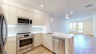 Located at 2966 W 7th St in Los Angeles, this well-appointed 1-bedroom, 1-bathroom unit offers a thoughtfully designed layout with modern finishes throughout. Light wood-style flooring flows continuously across the living areas, creating a warm, cohesive aesthetic complemented by crisp white walls.

The open-concept kitchen and living room form the heart of the unit. The kitchen is equipped with stainless steel appliances — including a French door refrigerator, range, and built-in microwave — paired with sleek, cream-toned cabinetry featuring under-cabinet lighting and a white quartz peninsula countertop with an integrated sink. The adjacent living area benefits from large windows and a glass door that invite abundant natural light and views of the surrounding neighborhood.

The bedroom is a comfortable, well-proportioned space with its own window providing additional natural light. A dedicated walk-in closet offers generous built-in shelving and hanging rods, providing ample organized storage. The full bathroom features large-format neutral tile flooring, a soaking tub with tiled surround, a vanity, and clean, understated finishes throughout.