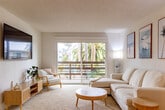 Located at 222 Columbia St in Santa Cruz, CA, this one-bedroom, one-bathroom unit offers a well-designed coastal-inspired layout across a single floor. The living room features plush carpeting, bright white walls, and a sliding glass door that opens to a private balcony framed by lush palm trees — filling the space with natural light and outdoor views. The open kitchen and dining area is equipped with light wood cabinetry, dark countertops, stainless steel appliances including an electric range, microwave, and refrigerator, and a full sink. A convenient in-unit washer is tucked alongside the kitchen. Track lighting and a ceiling fan illuminate the dining area, which comfortably accommodates a small table and chairs. The bedroom offers a generous footprint with plush carpeting, a large window with neighborhood views, a built-in closet with mirrored sliding doors, and a coastal wave mural that adds character to the room. The bathroom features wood-tone cabinetry, dark countertops, wood-look flooring, and a shower-tub combination accented by a nautical-themed curtain. Textured walls throughout lend a classic California feel to this well-appointed coastal retreat.