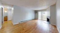 Located at 1250 S Clermont St in Denver, CO, this one-bedroom, two-bathroom unit at Infinity Flats offers a functional and comfortable single-floor layout. The living room is a standout space, featuring warm hardwood flooring, a textured ceiling, a wall-mounted AC unit, a baseboard heating system, and a tile-surround fireplace that serves as a central focal point. Sliding glass doors lead directly to a private balcony, filling the room with natural light. The dining area flows naturally from the living space, connected via a pass-through to the galley-style kitchen. The kitchen is equipped with warm wood cabinetry, dark tile backsplash, laminate countertops, and black appliances including a refrigerator, range, and microwave. The bedroom offers plush carpeting, a textured ceiling, a closet with bi-fold doors, and a baseboard heater beneath a window. Two bathrooms serve the unit, one featuring a full tub-shower combo with large-format tile surround. Throughout the unit, neutral gray walls, hardwood floors in the main living areas, and consistent trim work create a cohesive and clean aesthetic well-suited for everyday living.