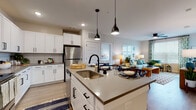 The Cadence Sugar Hill Type B4 residence offers a thoughtfully designed 2-bedroom, 2-bathroom single-floor layout in Sugar Hill, Georgia. The open-concept kitchen serves as the heart of the home, showcasing white shaker cabinetry with matte black hardware, quartz countertops, a subway tile backsplash, and a full suite of stainless steel appliances. A central island with a deep undermount sink and stylish pendant lighting provides both prep space and a casual dining option, flowing seamlessly into the living area. The living room is bright and welcoming, with large windows that invite natural light and a ceiling fan overhead. Both bedrooms feature plush carpeting, generous windows, and dedicated closets—one of which includes a walk-in with wire shelving for ample storage. The two bathrooms are finished with white cabinetry, granite countertops, undermount sinks, and matte black fixtures, maintaining a consistent and modern aesthetic throughout. Wood-look flooring runs through the main living areas, adding warmth and continuity. The unit's clean, neutral palette and contemporary design make it a versatile and comfortable place to call home.