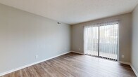 Located at 1000 Cooks Crossing Dr in Milford, Ohio, this single-floor residence offers a clean, modern aesthetic with thoughtfully updated finishes throughout. The open living area is highlighted by durable hardwood-style flooring, neutral gray walls, and a sliding glass door with vertical blinds that fills the space with natural light and provides access to an outdoor area. The layout flows naturally from the living space toward the kitchen and private rooms via a connecting hallway. The kitchen is well-equipped with light wood cabinetry extending to the ceiling for ample storage, granite-style countertops, a tile backsplash, a stainless steel sink, and a full suite of appliances including a refrigerator, dishwasher, and range. Bedrooms are carpeted for comfort and feature neutral tones, natural light from windows with blinds, and generous closet space — one bedroom includes a sliding door closet fitted with wire shelving for organized storage. The hallway connecting the rooms is clean and functional, maintaining the consistent neutral palette found throughout the residence. Overall, the space presents a practical and modern living environment with quality finishes and a bright, welcoming ambiance.