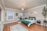 Located at 1733 N Cherokee Ave in the heart of Hollywood, Los Angeles, this 1-bedroom, 1-bathroom unit offers a thoughtfully designed single-floor layout. The spacious bedroom is a standout feature, showcasing an ornate embossed tin ceiling, an elegant crystal chandelier, and crown molding that lends the room a classic, refined character. Warm hardwood floors run throughout, complemented by neutral gray walls and white wainscoting trim. Two windows allow natural light to fill the room, creating a bright and welcoming atmosphere. A dedicated closet provides convenient storage directly off the bedroom. The bathroom retains a vintage charm with classic black-and-white octagonal tile flooring, a pedestal sink, and a full bathtub with shower. The compact kitchen is efficiently appointed with tile countertops, a gas range, refrigerator, and a window that brings in natural light and garden views. Additional utility is provided by an in-unit laundry area and a hallway connecting the living spaces. This unit blends period architectural details with functional living, making it a distinctive offering in one of Los Angeles' most iconic neighborhoods.