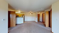 This single-floor residential unit offers a functional and well-organized layout designed for comfortable everyday living. The open-concept living and dining area is generously sized, featuring neutral-toned carpet, warm wood baseboards, and a ceiling fan that promotes airflow and comfort. A curved breakfast bar seamlessly connects the living space to the kitchen, providing both a visual boundary and a casual dining or workspace option.

The galley-style kitchen is efficiently designed with ample honey-toned wood cabinetry on both sides, offering abundant storage. Stainless steel appliances — including a refrigerator, electric range, and dishwasher — complement the neutral countertops, while wood-look flooring adds warmth underfoot.

The unit includes multiple bedrooms, each finished with soft carpet, neutral walls, and windows that frame outdoor greenery and views of a surrounding balcony railing, allowing natural light to fill the rooms. Ceiling fans in the bedrooms enhance ventilation and comfort.

The bathroom is cleanly appointed with wood-look tile flooring, a full soaking tub with shower, a vanity with warm wood cabinetry, and a large mirror. A spacious walk-in closet is also accessible from the main living area, providing generous storage throughout the unit. The overall ambiance is clean, neutral, and move-in ready.