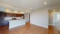 Located at 114 E. 5th Street in Columbus, Ohio, this single-floor residence showcases a thoughtfully designed open-concept layout with contemporary finishes throughout. The kitchen serves as a central highlight, featuring rich dark-toned cabinetry, a classic white subway tile backsplash, a full suite of stainless steel appliances including a range, microwave, and refrigerator, and a large central island with a light quartz countertop and integrated sink. A distinctive tray ceiling with recessed lighting adds architectural depth to the kitchen and living area. Warm hardwood-style flooring flows seamlessly through the main living spaces, creating a cohesive and inviting atmosphere. The spacious living area benefits from recessed lighting and neutral gray walls, offering a clean, versatile canvas. The bedroom is carpeted for comfort and features multiple windows with horizontal blinds that allow ample natural light. The bathroom is well-appointed with a frameless glass-enclosed walk-in shower clad in large-format marble-look tile, a dark vanity with a white countertop, and hardwood-style flooring. Additional highlights include a generously sized walk-in closet with wire shelving, providing excellent storage capacity. The unit's neutral palette and modern finishes make it a polished and functional living space.