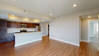 Located at 114 E. 5th Street in Columbus, Ohio, this single-floor residence showcases a thoughtfully designed open-concept layout with contemporary finishes throughout. The kitchen serves as a central highlight, featuring rich dark-toned cabinetry, a classic white subway tile backsplash, a full suite of stainless steel appliances including a range, microwave, and refrigerator, and a large central island with a light quartz countertop and integrated sink. A distinctive tray ceiling with recessed lighting adds architectural depth to the kitchen and living area. Warm hardwood-style flooring flows seamlessly through the main living spaces, creating a cohesive and inviting atmosphere. The spacious living area benefits from recessed lighting and neutral gray walls, offering a clean, versatile canvas. The bedroom is carpeted for comfort and features multiple windows with horizontal blinds that allow ample natural light. The bathroom is well-appointed with a frameless glass-enclosed walk-in shower clad in large-format marble-look tile, a dark vanity with a white countertop, and hardwood-style flooring. Additional highlights include a generously sized walk-in closet with wire shelving, providing excellent storage capacity. The unit's neutral palette and modern finishes make it a polished and functional living space.