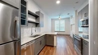 Located at 3233 Harmon Ave in Austin, TX, this efficiently designed single-floor studio offers a thoughtfully utilized layout across a compact footprint. The open-concept kitchen and living area serves as the heart of the space, featuring sleek gray shaker-style cabinetry, marble-look quartz countertops, and a hexagonal tile backsplash. A full suite of stainless steel appliances — including a refrigerator, electric range, built-in microwave, and dishwasher — provides modern functionality. A peninsula counter extends into the living area, offering additional prep space and a natural visual division between the kitchen and living zones. Warm wood-look plank flooring runs throughout the main living areas, complementing the cool gray tones of the cabinetry and walls. The living room benefits from natural light through large windows fitted with horizontal blinds, while a ceiling fan adds comfort. Recessed lighting and open shelving complete the kitchen's contemporary aesthetic. The bathroom features light tile flooring, a marble-look vanity countertop, and direct access to a dedicated closet equipped with multi-level shelving and hanging rods. Clean white walls and consistent finishes throughout create a cohesive, modern ambiance well-suited to Austin's urban lifestyle.