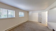 Located at 1400 Twombly Rd in DeKalb, Illinois, this one-bedroom, one-bathroom unit offers a practical and well-organized layout across a single floor. The open-concept living and kitchen area creates a sense of spaciousness, with the kitchen featuring bold dark cabinetry that contrasts cleanly against white countertops and a central breakfast bar peninsula. Standard appliances, including a range and refrigerator, are neatly integrated alongside a sink, making the kitchen both functional and visually striking. The transition from wood-look flooring in the entry and kitchen to plush carpeting in the living area adds warmth and definition to the space. The generously sized bedroom is carpeted and bathed in natural light from two windows fitted with horizontal blinds, offering a bright and comfortable retreat. A dedicated closet provides convenient storage. The bathroom includes an enclosed glass-door shower stall with chrome fixtures, offering a clean and efficient design. Baseboard heating runs along the living area walls, ensuring warmth throughout the unit. The overall aesthetic is clean and neutral, with white walls and simple finishes that offer a versatile canvas for personalization. This unit is well-suited for a single occupant seeking a compact yet fully functional home in DeKalb.