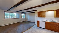 Located at 321 Seventh St N in Sartell, Minnesota, this two-bedroom, one-bathroom single-floor unit offers a practical and comfortable layout. The combined kitchen and living area is a standout space, featuring rich oak cabinetry, white appliances including a range, dishwasher, and refrigerator, light vinyl flooring, and a textured ceiling with distinctive dark exposed wood beams. A ceiling fan and wall-mounted air conditioning unit add to the room's functionality. Large windows in the living area flood the space with natural light and provide views of surrounding greenery.

Both bedrooms are carpeted and served by baseboard heating, with wood-framed windows that bring in additional natural light. The primary bedroom is a generous size, offering ample room for furnishings. One bedroom features a double-door wood closet, providing convenient storage. The bedrooms share access via connecting hallways that run through the unit.

The bathroom is finished with classic white tile walls, a mosaic tile floor, an oak vanity with a white sink, and a large mirror with overhead lighting. Warm wood trim and door frames are consistent throughout the unit, contributing to a cohesive, traditional aesthetic. The textured ceilings appear in multiple rooms, adding a characteristic touch to this well-laid-out Sartell residence.