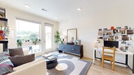 Located in Atlanta, GA, this one-bedroom, one-bathroom residence offers a thoughtfully designed layout across a single living floor. Light wood flooring flows throughout, lending warmth and continuity to the space.

The open-concept living room is bright and inviting, anchored by French doors that open to a private balcony with views of the surrounding neighborhood. Recessed lighting and clean white walls create an airy atmosphere, while built-in wall shelving adds both style and functionality.

The kitchen is a standout feature, boasting dark cabinetry paired with a white subway tile backsplash and light quartz countertops. Stainless steel appliances — including a full-size refrigerator, range, microwave, and dishwasher — are complemented by a generous island with pendant lighting overhead, ideal for casual dining or meal prep.

The bedroom is a comfortable retreat, featuring large windows that invite abundant natural light and offer open city views. A dedicated closet provides practical storage.

The bathroom continues the modern aesthetic with dark cabinetry, a wide vanity mirror, and light wood-style flooring. A walk-through layout leads to an additional closet area, enhancing the unit's overall storage capacity. This residence combines contemporary design with everyday functionality in a well-connected Atlanta location.