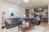 This single-story residence at River Pointe in Carrollton, Georgia offers a thoughtfully designed layout with a welcoming flow from room to room. The entryway greets visitors with built-in open shelving and a clear sightline through an arched passage into the living areas beyond, establishing an immediately open and connected feel.

The living room is bright and comfortable, featuring light wood-style flooring, a large window that draws in natural light, and a direct-access exterior door — ideal for easy indoor-outdoor movement. The kitchen is efficiently arranged with white cabinetry, light stone-look countertops, and stainless steel appliances, providing a clean and functional cooking space.

The hallway acts as a central hub, connecting the bedrooms and bathrooms with a tasteful console and framed artwork adding a curated touch. Bedrooms are carpeted for warmth and comfort, each receiving natural light through windows dressed with draping curtains. The bathrooms are well-appointed with white cabinetry vanities, wood-style tile flooring, and tub-shower combinations.

Throughout the home, neutral walls in soft gray and beige tones create a calm, cohesive palette. The overall ambiance is clean, comfortable, and move-in ready, reflecting a consistent attention to detail across every space.