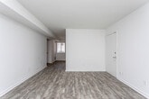 This single-floor residence at 1156 Woodland Ave NE in Atlanta, Georgia offers a clean, modern aesthetic throughout its well-designed layout. The open living and dining areas feature durable wood-look flooring in a warm gray tone, crisp white walls, and multiple windows dressed with horizontal blinds that invite natural light while maintaining privacy. The space flows naturally from the entry through the main living area toward the rest of the home.

The kitchen is a standout feature, equipped with sleek white cabinetry extending to the ceiling for generous storage, granite-look countertops, a white subway tile backsplash, and a full suite of stainless steel appliances including a gas range, microwave, refrigerator, and dishwasher. A window above the sink adds natural light to the workspace.

The bedrooms are carpeted for comfort, with neutral tones and windows overlooking the surrounding greenery. The primary bedroom is particularly well-appointed, offering dual closets with ample hanging space and direct access to the bathroom. The bathroom features full white tile surrounding a soaking tub and shower combination, tile flooring, and a window that provides ventilation and natural light. The overall ambiance throughout the home is bright, clean, and move-in ready.