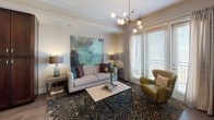 This single-floor residence offers a thoughtfully designed layout that balances style and functionality across its key living areas. The kitchen serves as a standout centerpiece, showcasing rich dark-wood cabinetry, granite countertops, stainless steel appliances including a French door refrigerator, a subway tile backsplash, and a central island with seating — all illuminated by pendant lighting and a track light system overhead. Wood-look flooring grounds the space with warmth, flowing seamlessly into the adjacent living area. The living room is bright and welcoming, featuring large windows dressed with blinds and drapes that invite natural light, a tray ceiling with a modern chandelier, and an open feel well-suited for relaxing or entertaining. The bedroom is a calm retreat with plush carpet, natural light from large windows, and a ceiling fan for comfort. A walk-in closet provides generous built-in shelving and hanging storage. The full bathroom is finished with a dark wood vanity, granite countertops, tile flooring, and a full tub-shower combination surrounded by floor-to-ceiling gray tile, creating a clean and polished aesthetic. Together, these spaces form a cohesive, modern living environment with high-quality finishes throughout.